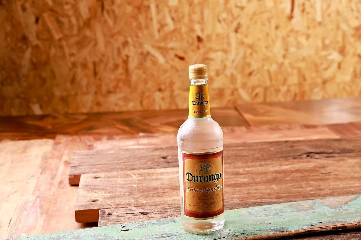 Don Julio 테킬라 단독 제품 촬영 — 라임 조각과 샷잔이 함께한 나무 테이블 위 주류 사진