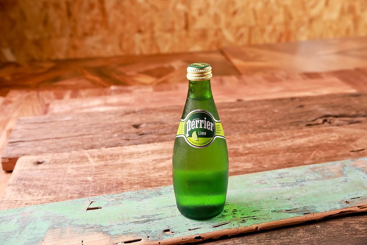 Perrier 라임 탄산수 병 단독 제품 촬영 — 나무 테이블 레스토랑 음료 메뉴 사진