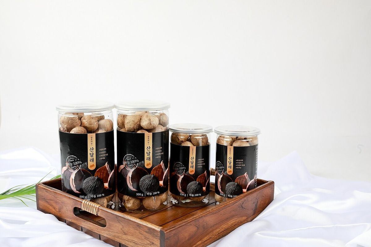 산달래 흑마늘 4종 병 라인업 — 원목 크레이트 위 흰 천 배경